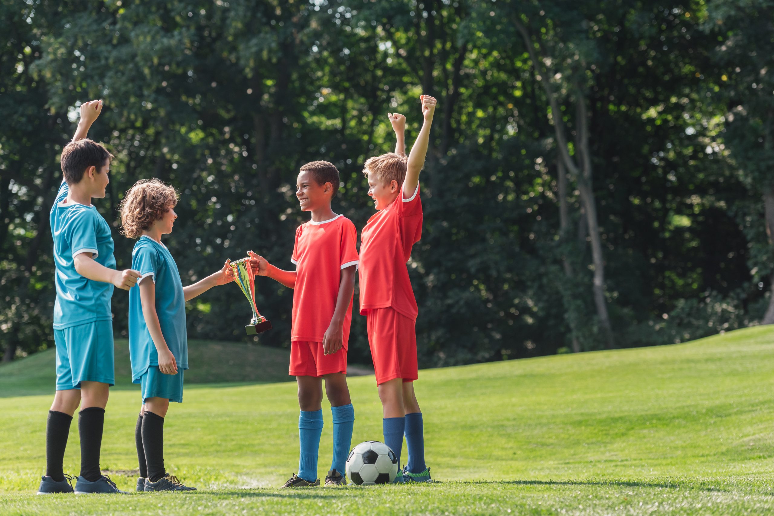 selective focus of cute multicultural kids gesturing near football